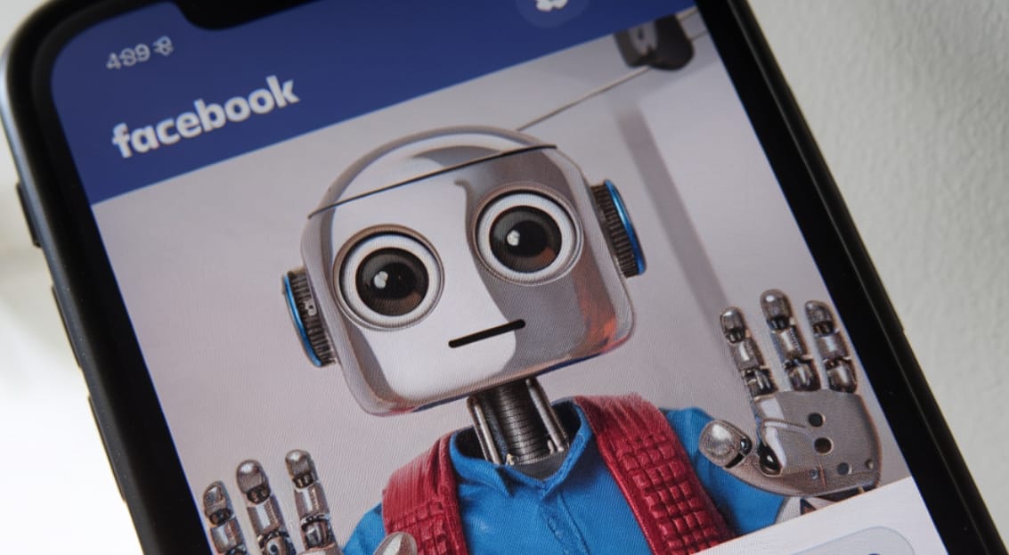 A photo of a smartphone screen displaying a Facebook AI-generated account. The account has a profile picture of a robot.