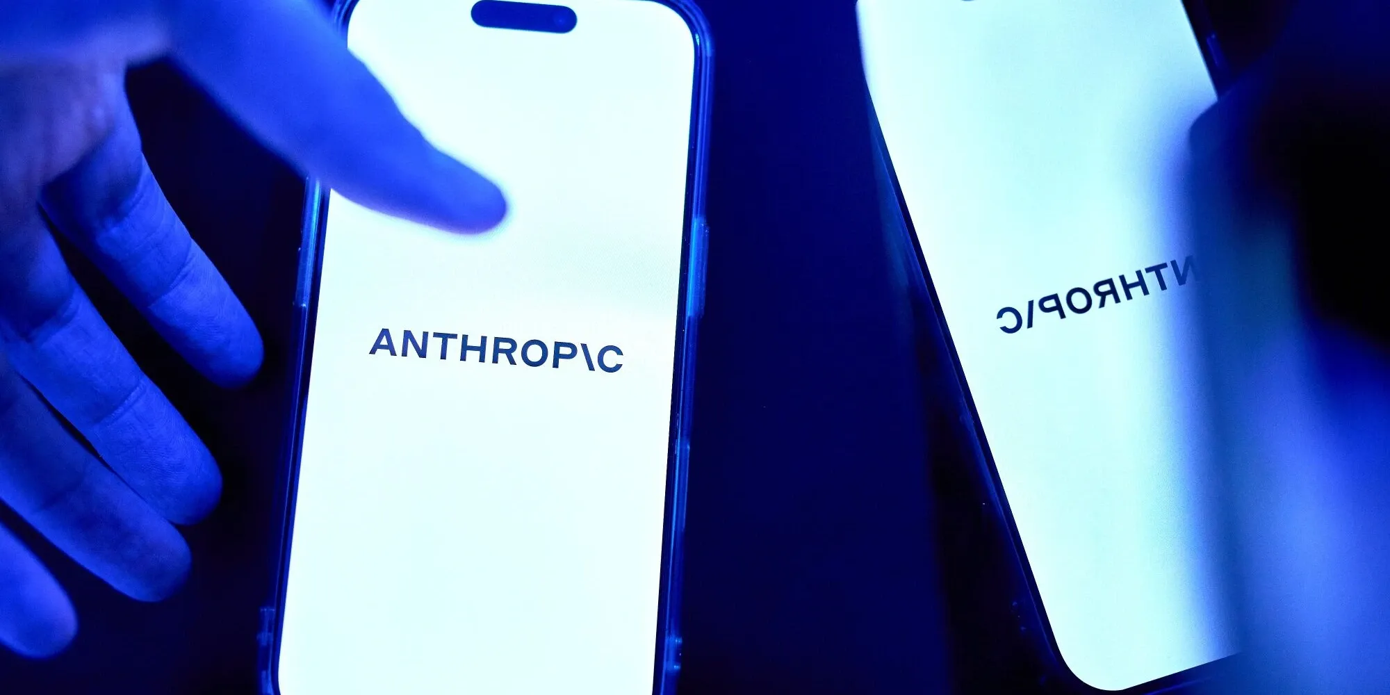 Anthropic logo on two smartphone screens under blue light