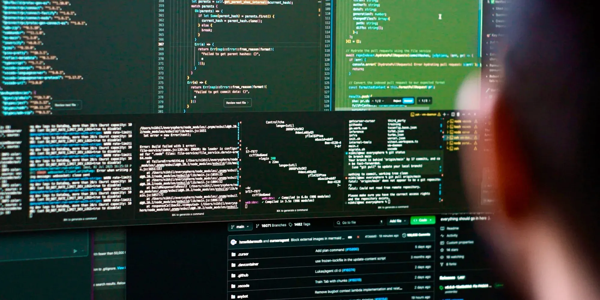 A developer looks at code on large monitors