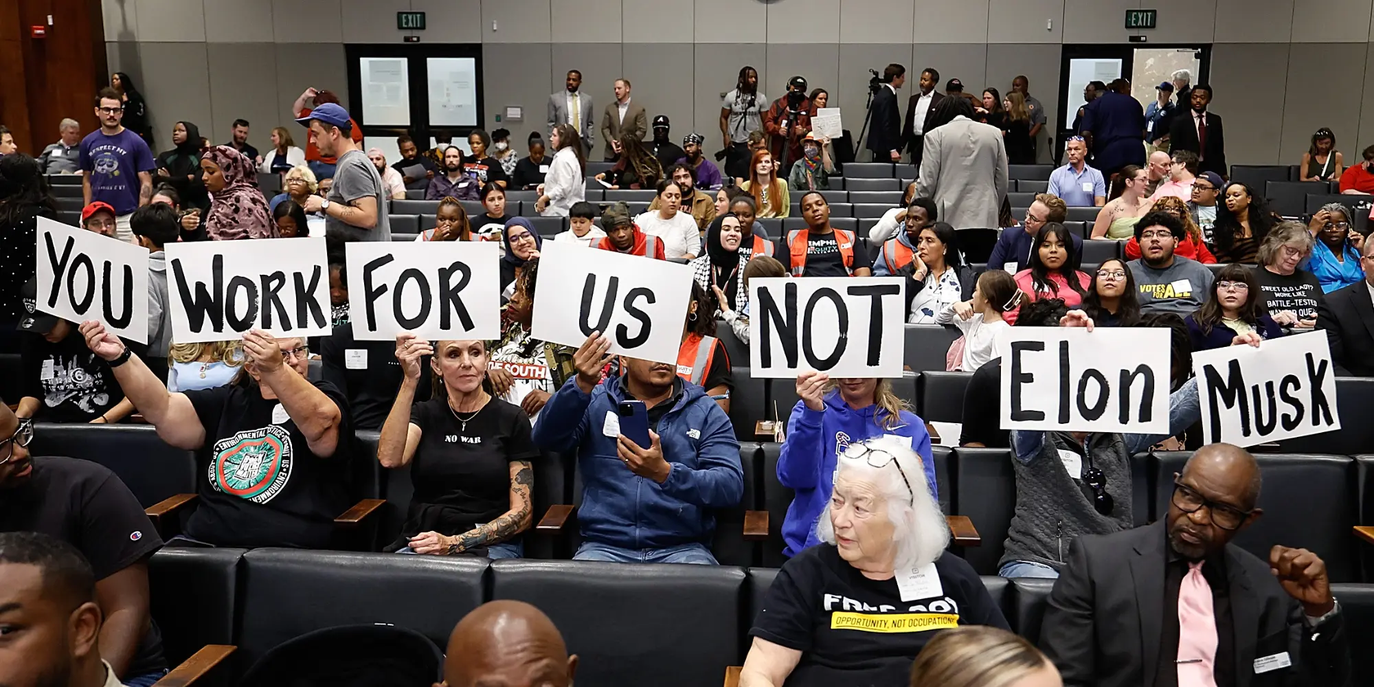 Residents hold signs reading You work for us not Elon Musk at a Memphis City Council meeting