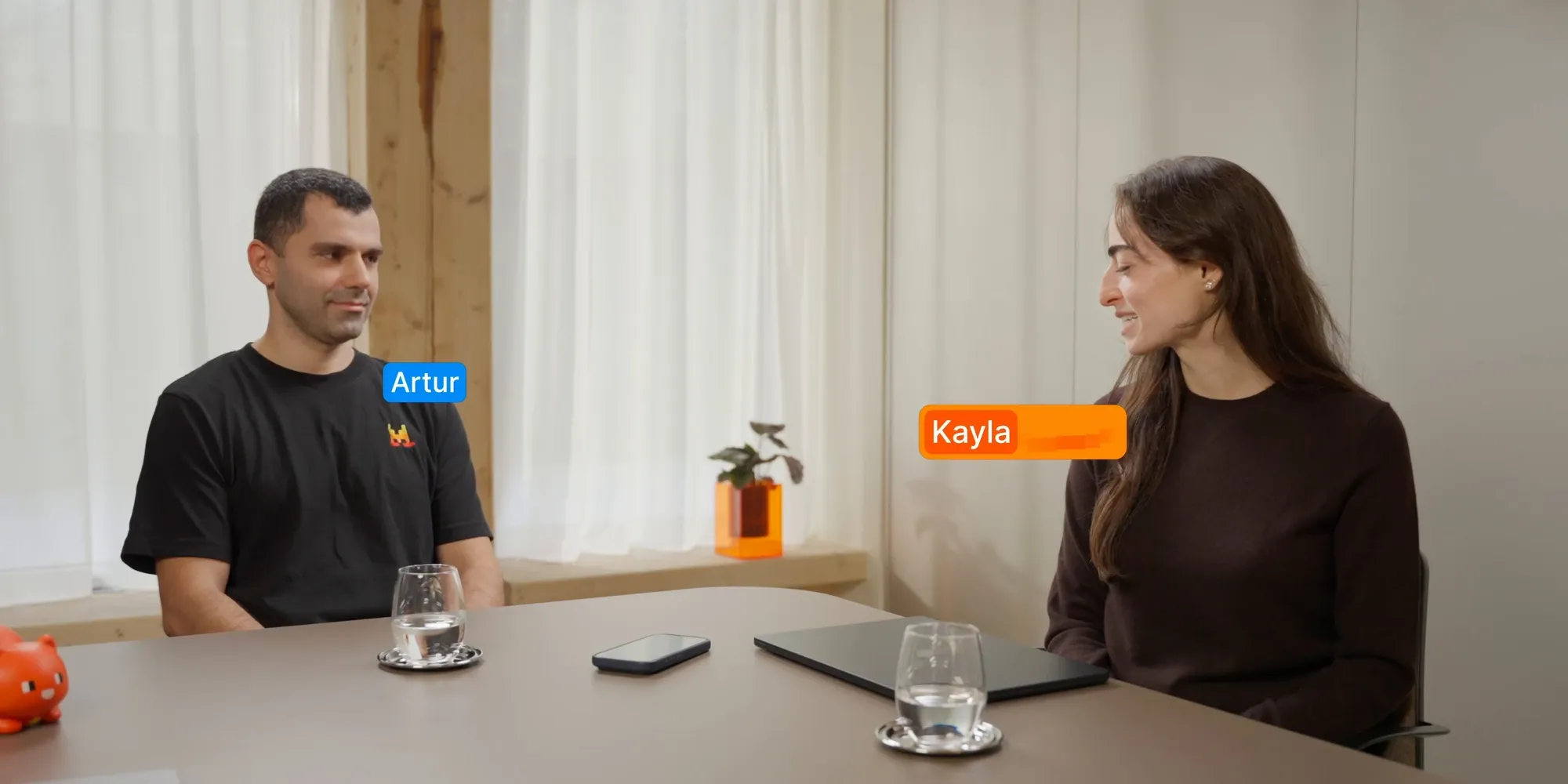Two people at a table in Mistral's Voxtral 3 demo, labeled by speaker