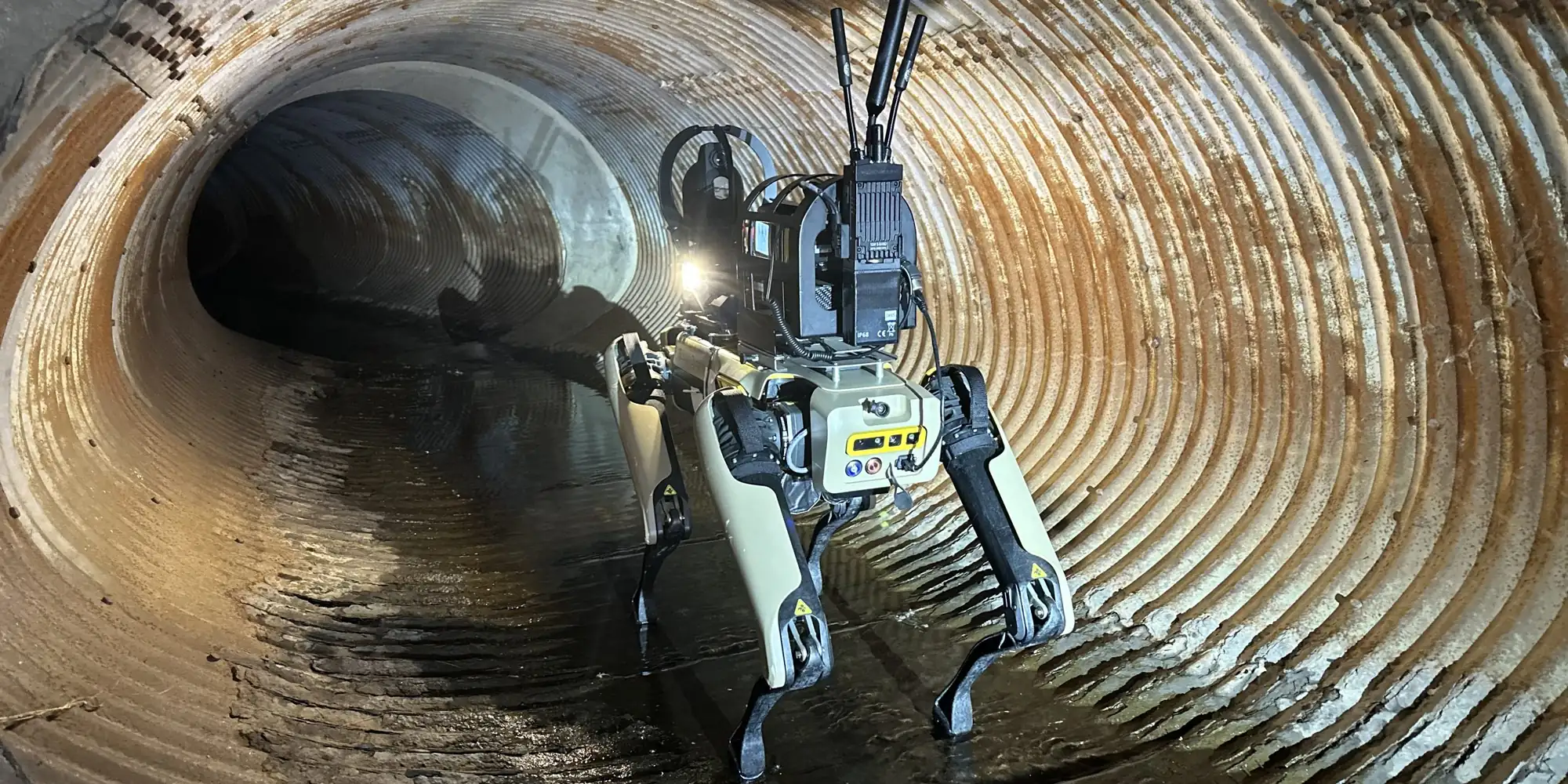 A modified Spot robot dog with antennas walking through a tunnel