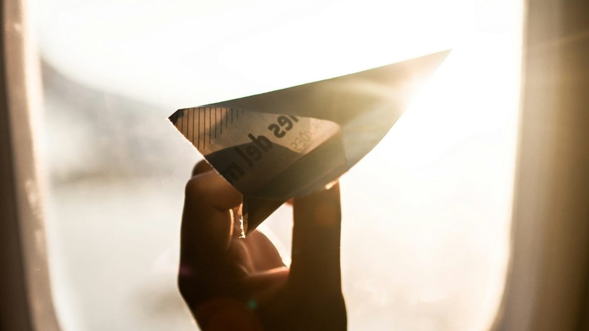 A hand holding a folded paper airplane
