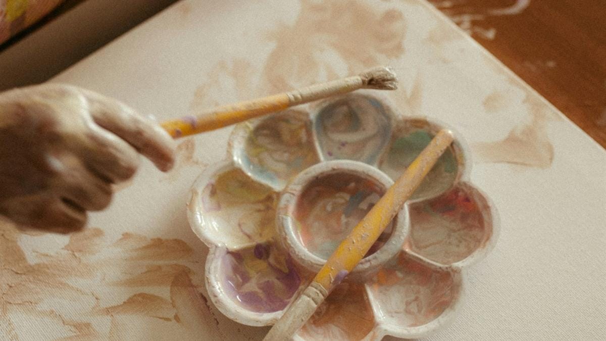Hands working with paint and brushes, illustrating human creative effort